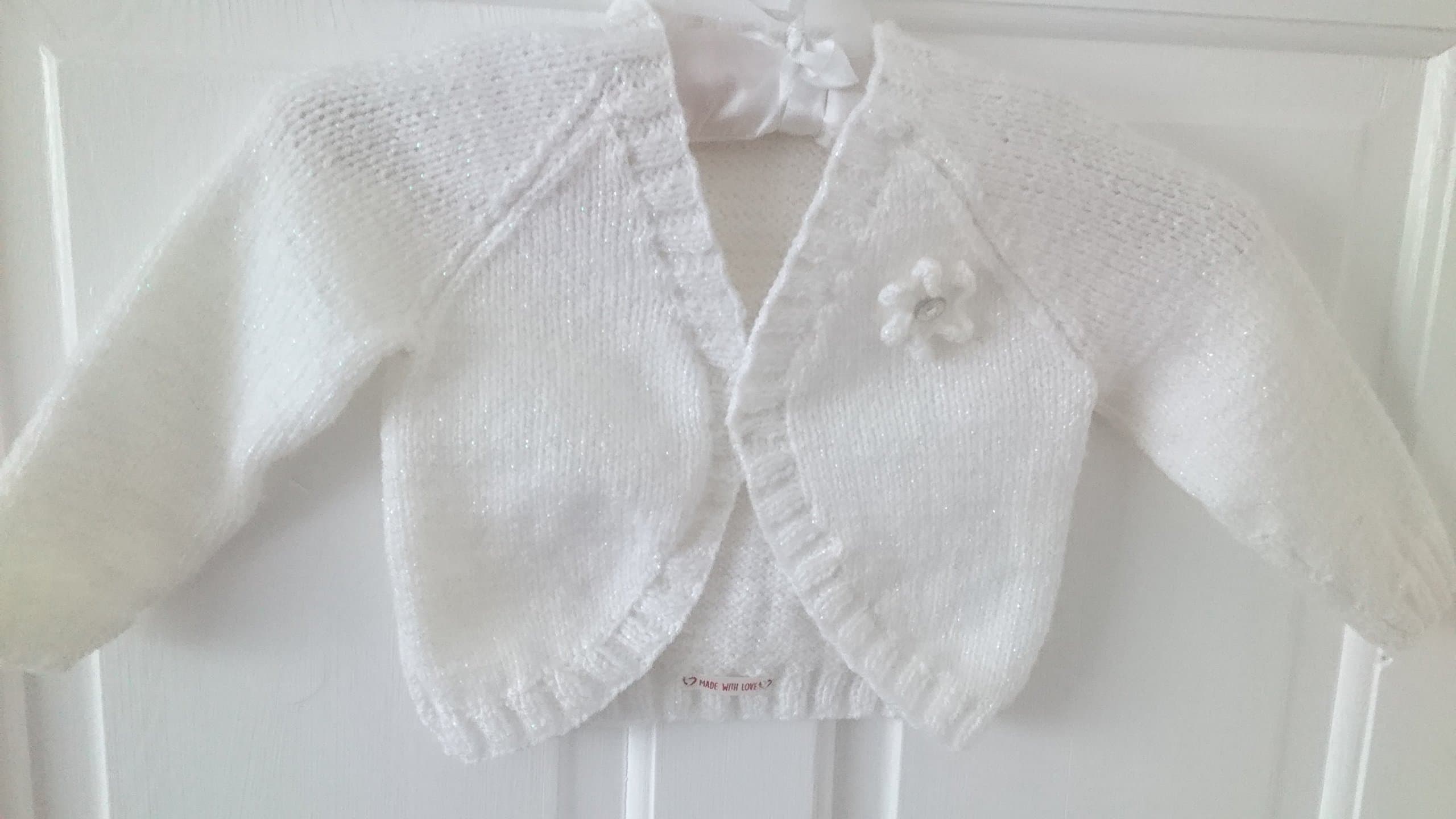 Lorenzo - age 2 - 3 yrs little girls hand knitted white bolero cardigan. Sparkle wool with knitted flower detail.
